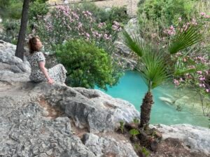 Woman sitting beside turquoise pool at Les Fonts d’Algar Spain