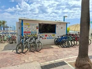 Sun Bikes bicycle rental shop on Marbella seafront promenade with bikes and rental prices