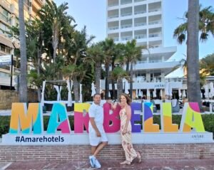 Couple posing by the colourful Marbella sign on the seafront near Amare Beach Hotel