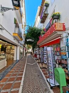 Whitewashed street in Marbella Old Town with flowers traditional lamps and cafe signs