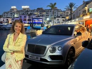 Puerto Banús Nightlife: Our First-Hand Marbella Guide Woman standing beside a luxury car near Puerto Banús marina at night