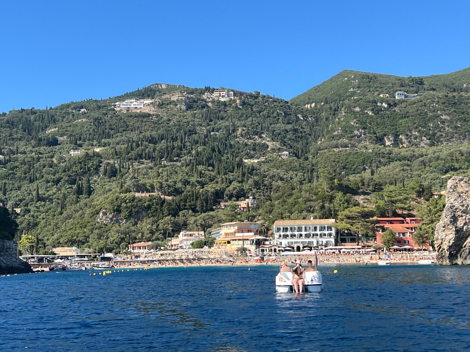 Paleokastritsa waterfront and green hills viewed from a boat