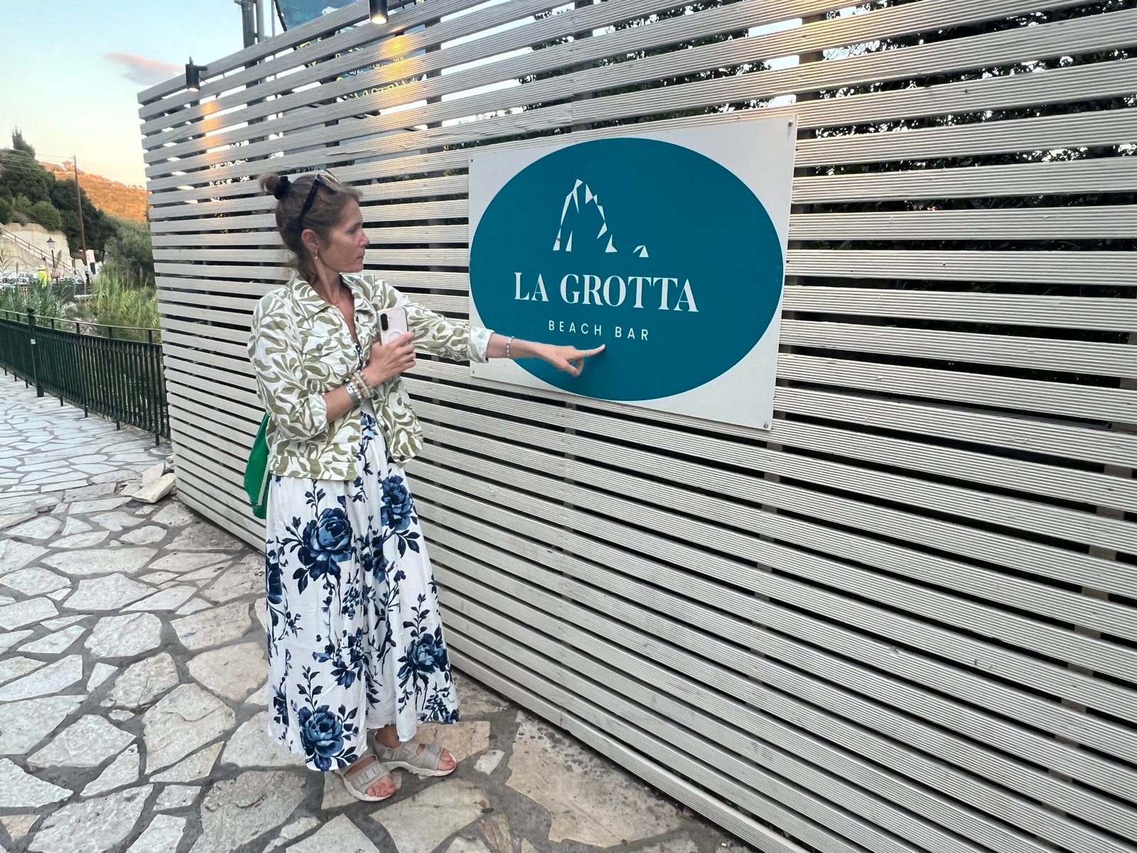 Woman looking at the La Grotta sign beside the entrance in Paleokastritsa