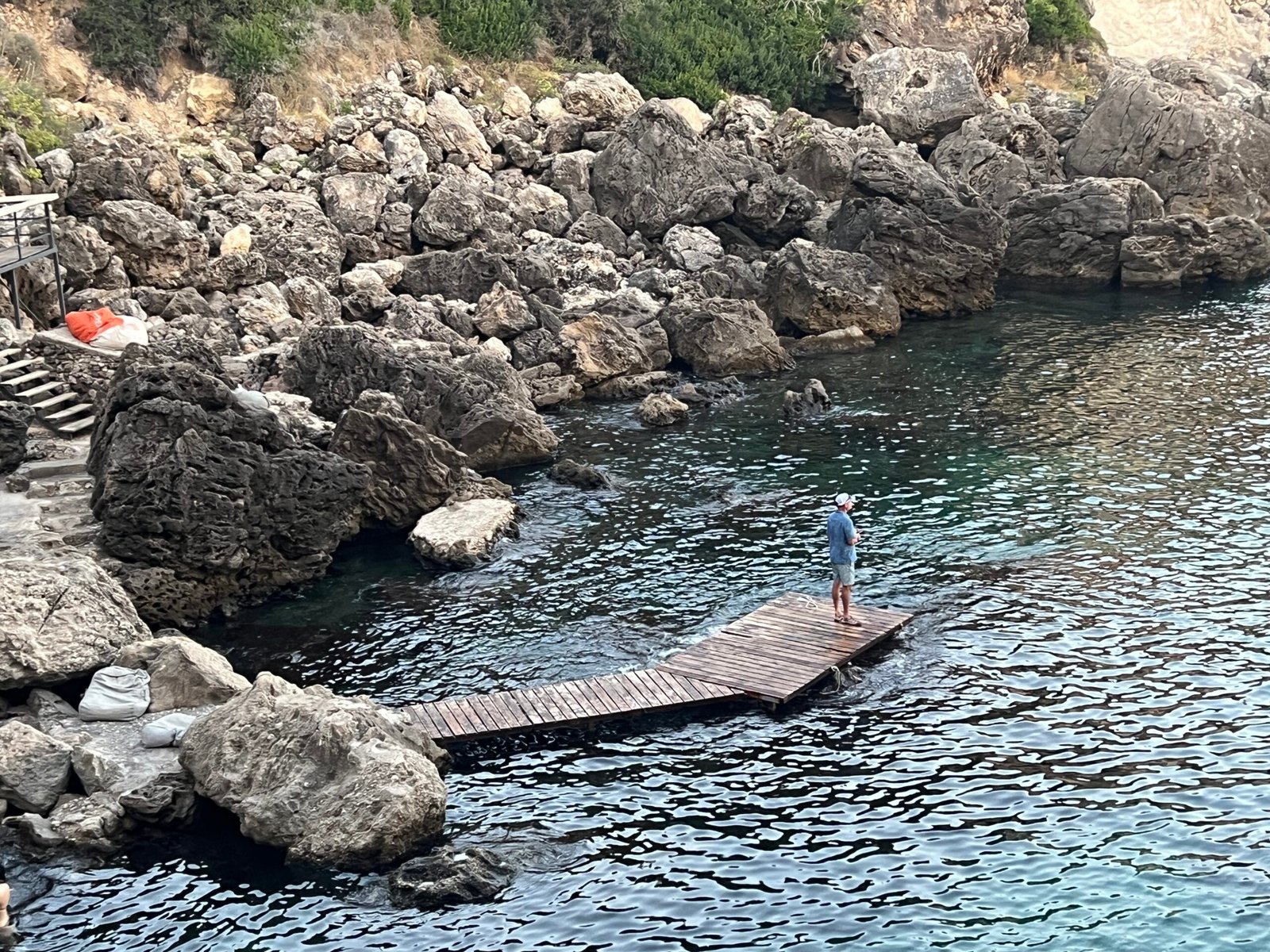 Wooden platform surrounded by water and rocks at La Grotta