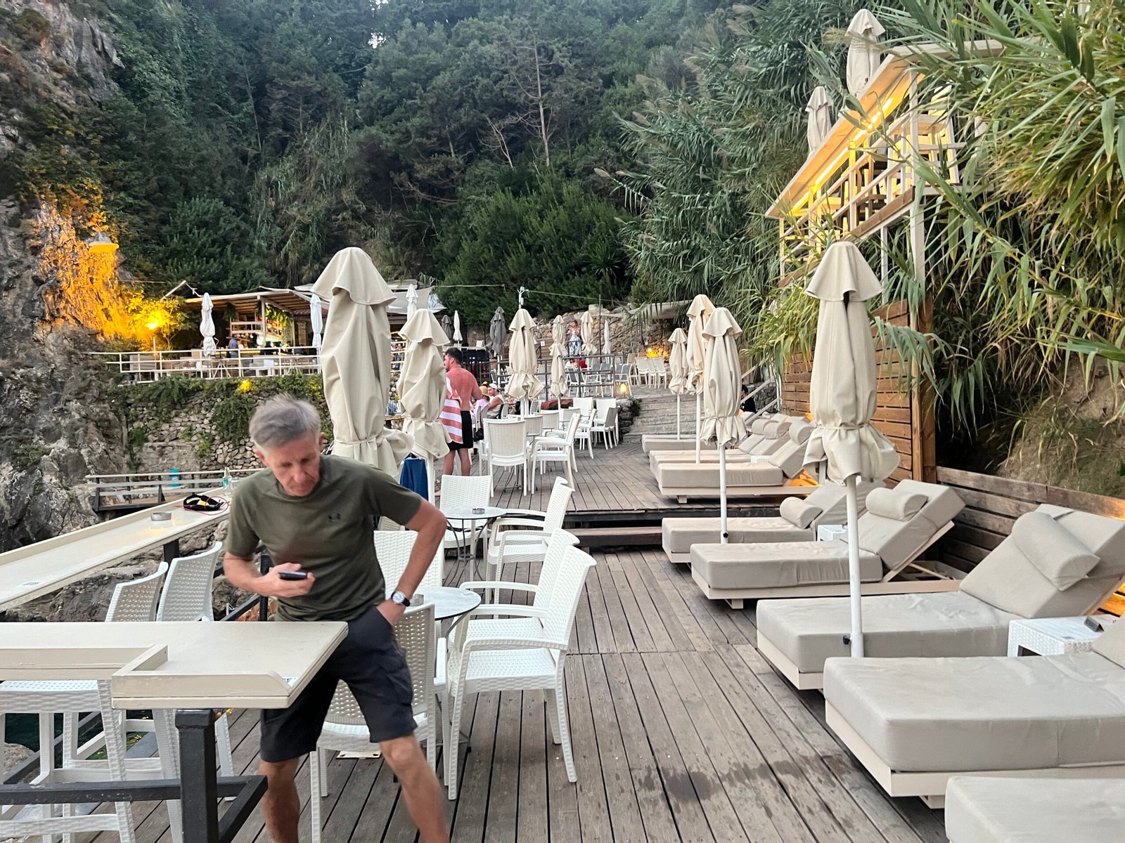 White loungers and tables on the wooden terrace at La Grotta Corfu