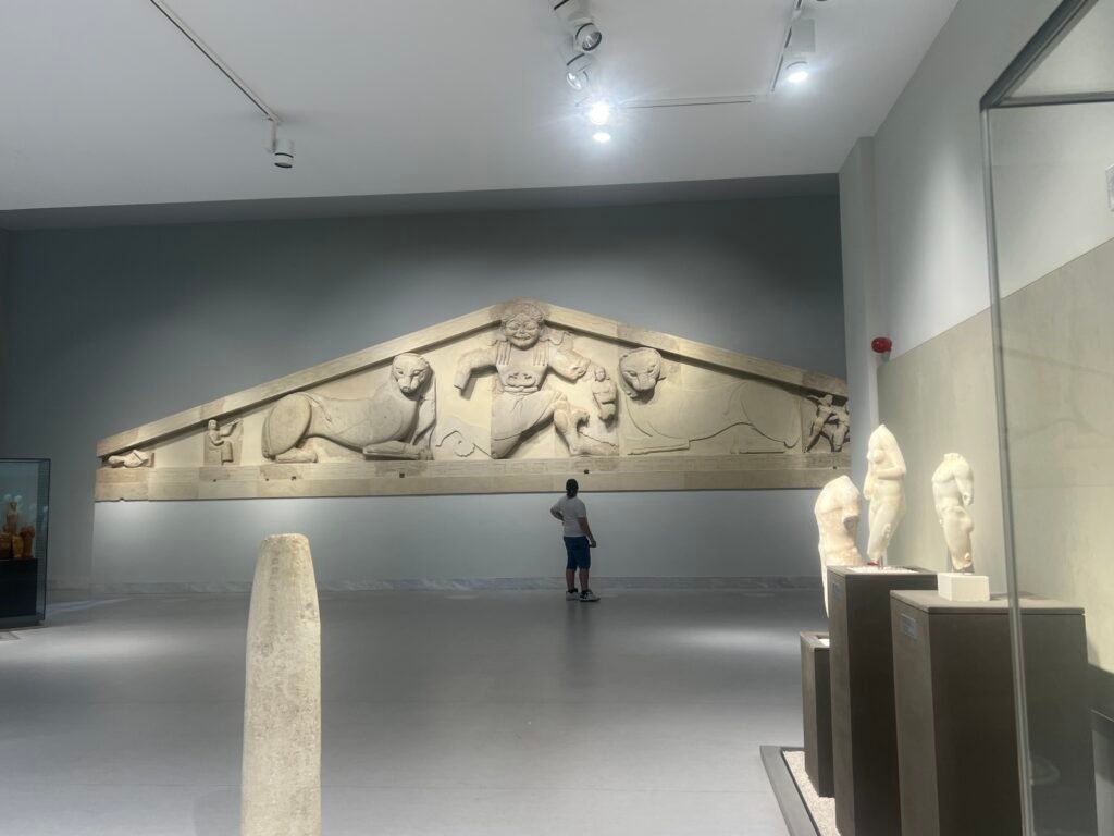The Gorgon pediment displayed across the far wall of the museum gallery.