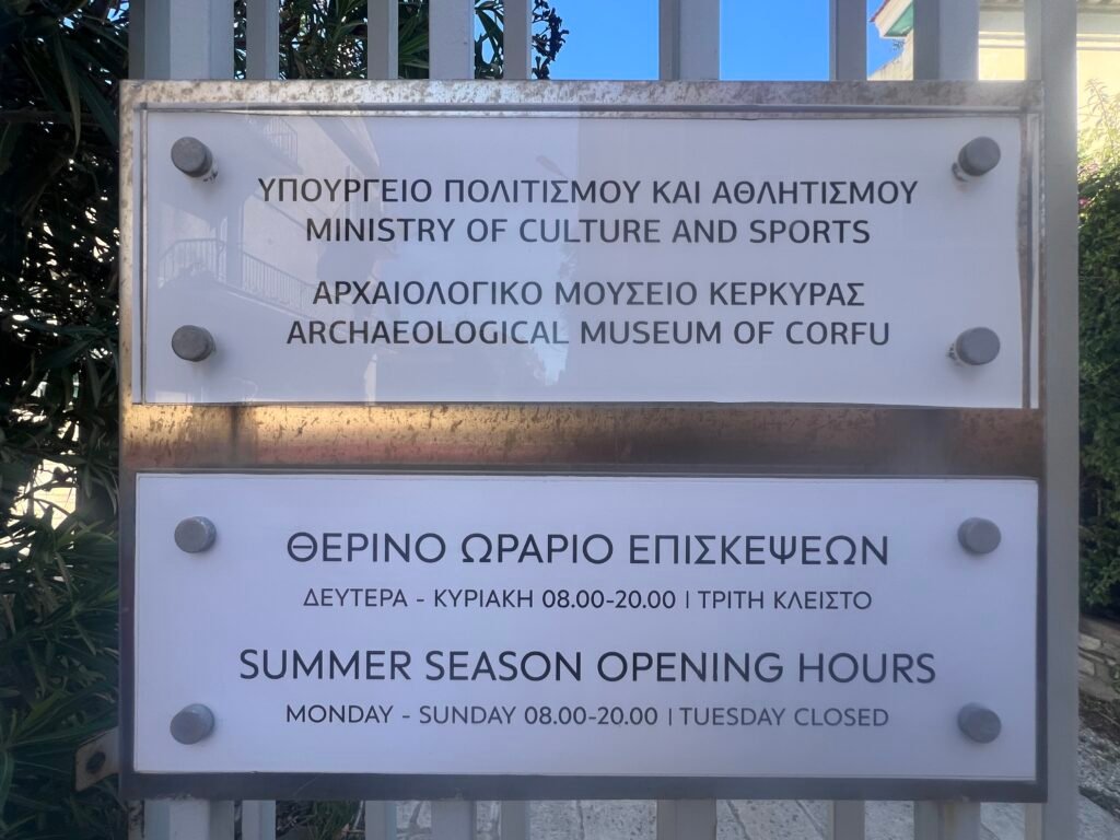 The entrance sign showing summer hours of 08:00–20:00, with Tuesday closed.