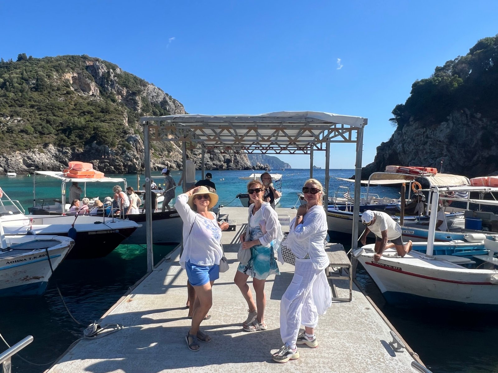 Three visitors beside the wooden boat jetty in Paleokastritsa