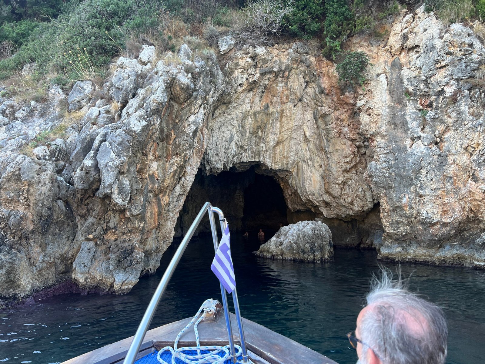 Small boat approaching a dark cave entrance in Paleokastritsa