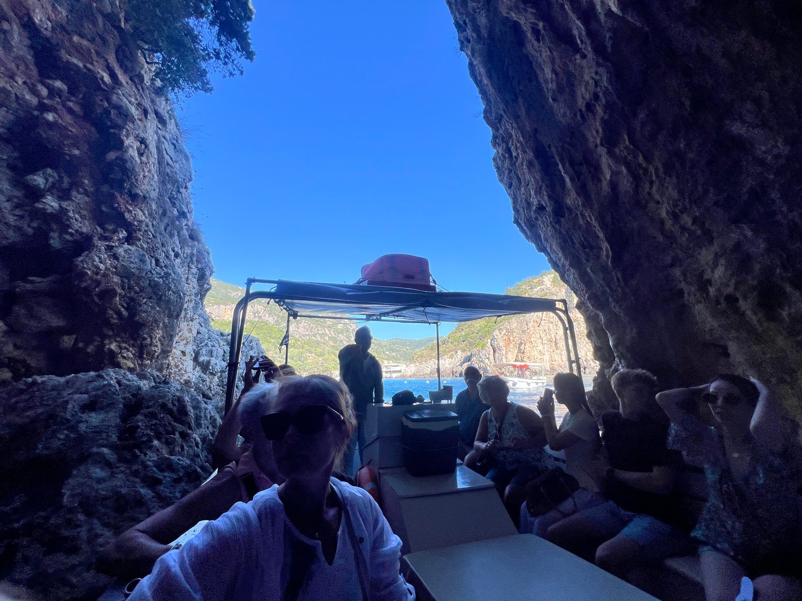 View out of a narrow sea cave towards a sightseeing boat and blue sky