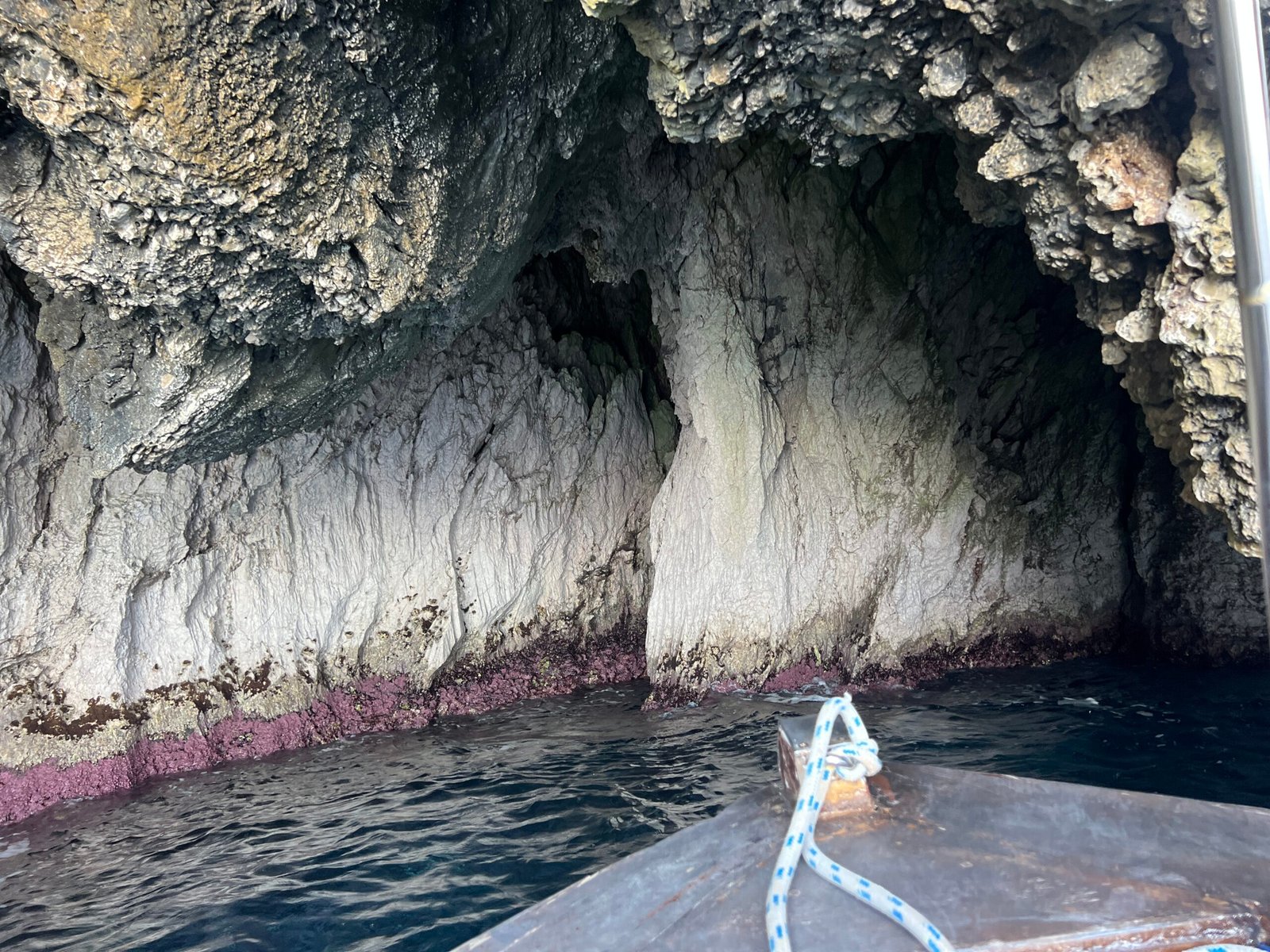 Pale rock walls and purple waterline inside a Paleokastritsa cave