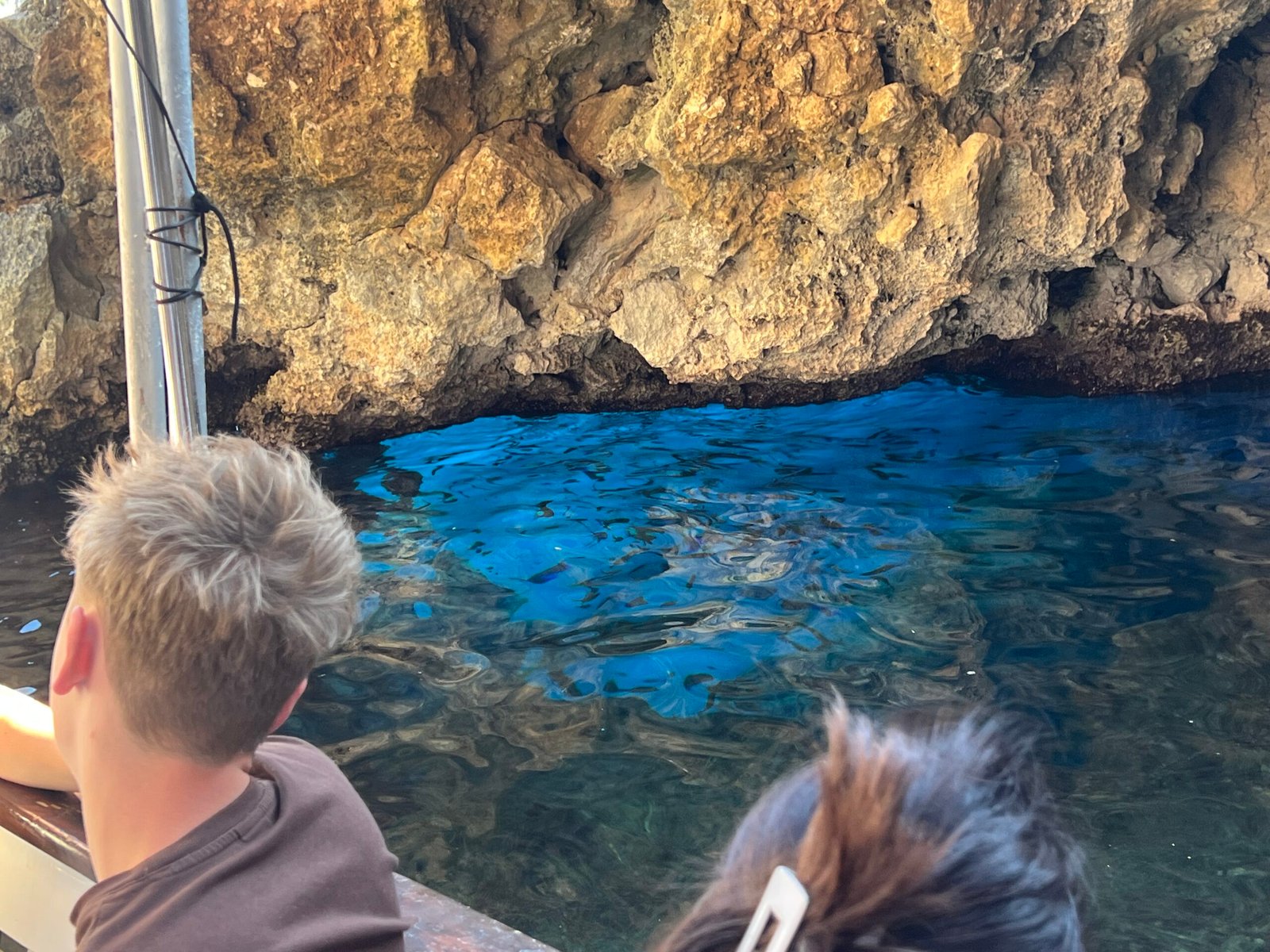 Bright blue water beneath golden rock walls at the Blue Eye cave