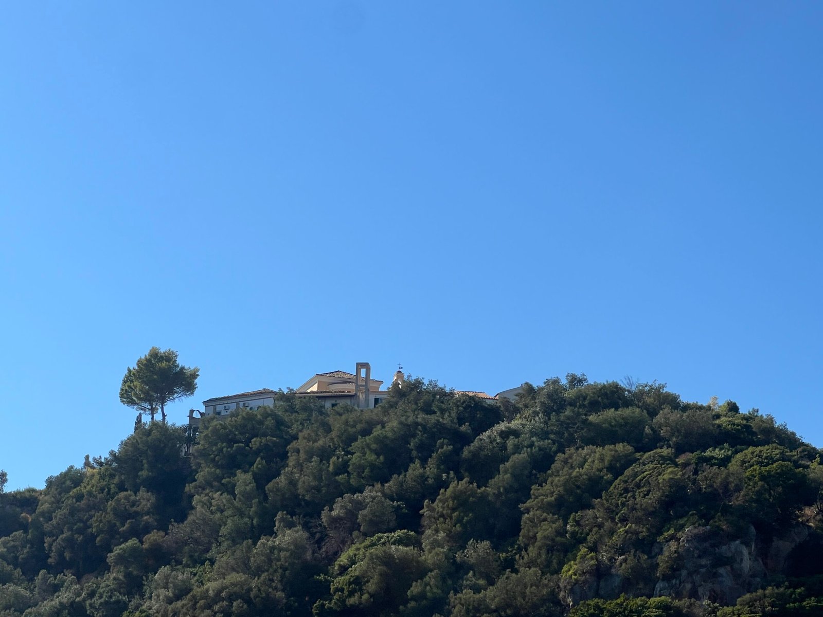 Paleokastritsa Monastery and palm tree on the wooded hill seen from the sea