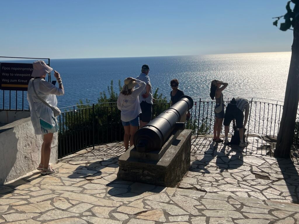 Cannon and visitors at a sea-facing viewpoint near Paleokastritsa Monastery